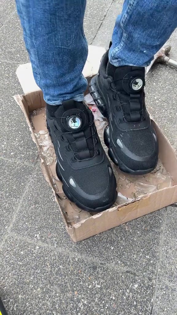 Zapatillas de seguridad pisando una caja con cristales rotos